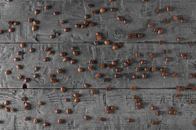 Coffee beans randomly scattered on a black wooden table.
