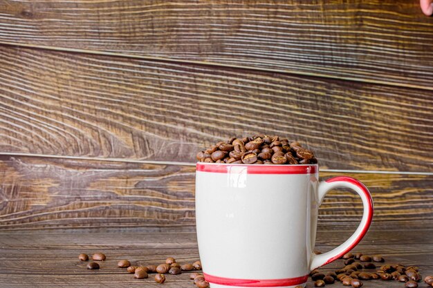 木製の床の上にあるカップに焼かれたコーヒー豆