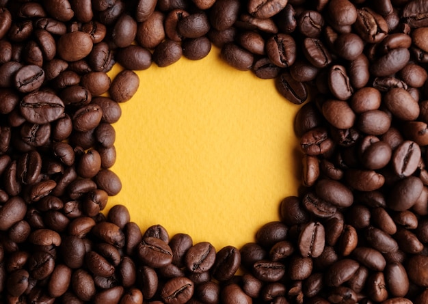 Coffee beans round frame at yellow background. Copy space