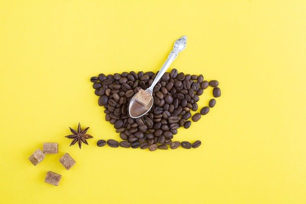 Coffee beans in the shape of a cup on the yellow background Top view Creative composition