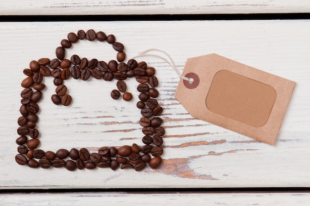 Coffee beans in a shape of handbag with handle. White wooden planks on surface.