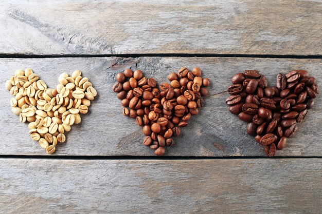 Coffee beans in shape of hearts on wooden background