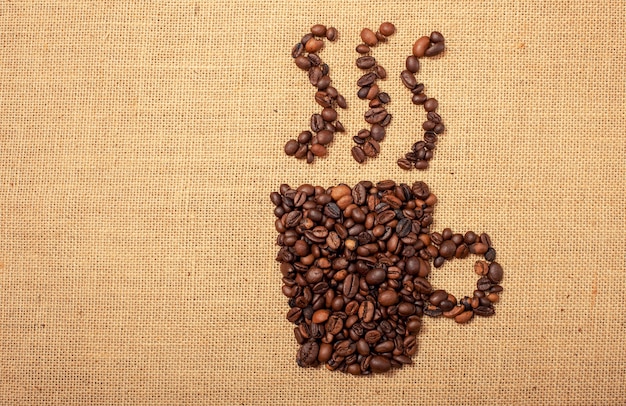 Coffee beans shaped as cup over a jute cloth background