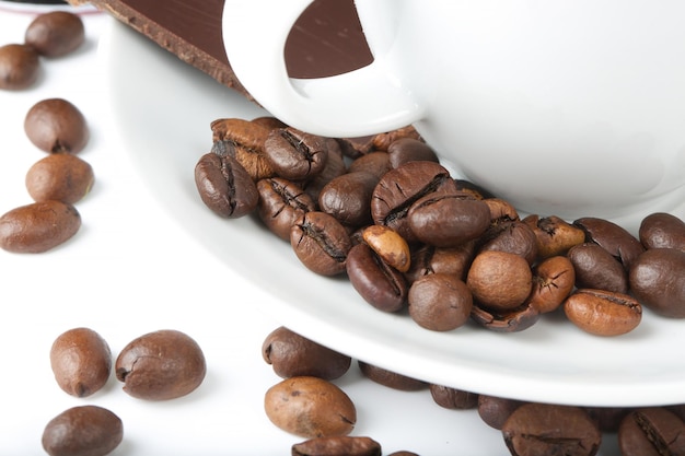 Coffee beans on a small white coffee plate.Closeup