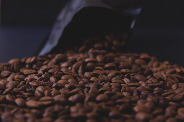 Coffee beans spill out of a black pack.