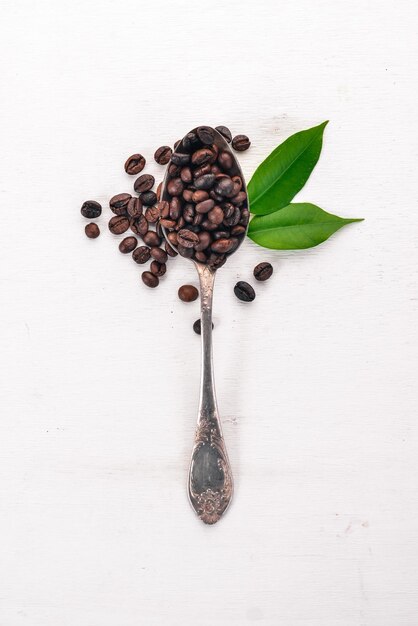 Coffee beans On a spoon lie on a wooden background Top view Copy space