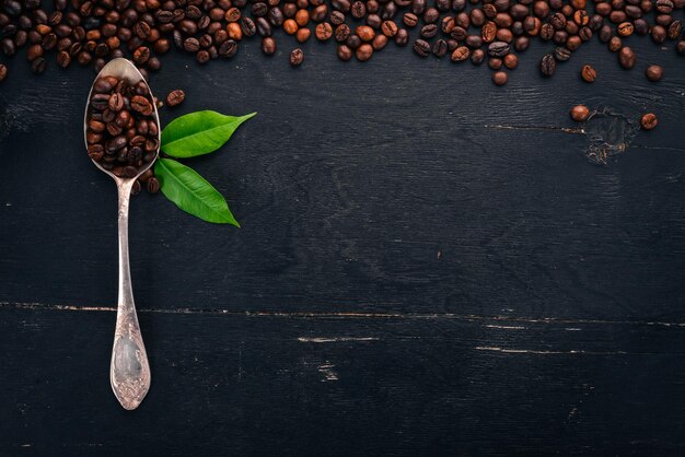 Coffee beans On a spoon lie on a wooden background Top view Copy space