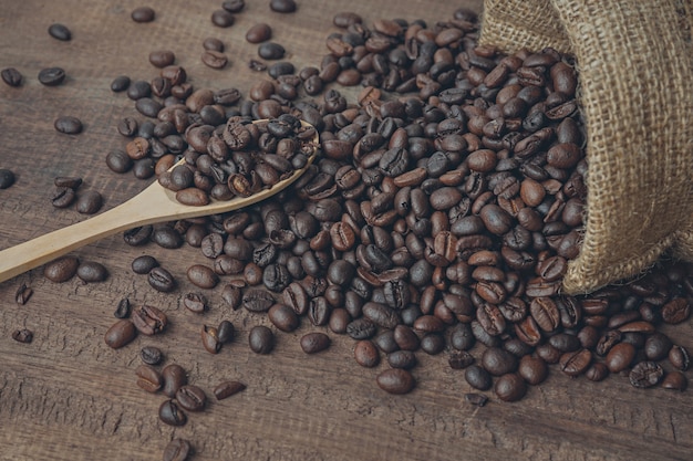 coffee beans in spoon on wood table background.