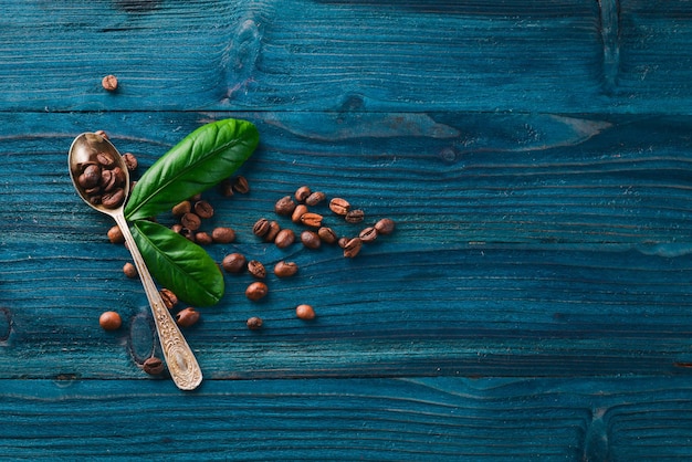 Coffee beans in a spoon on a wooden background Top view Free space for text