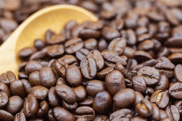 커피 콩 질감 또는 커피 콩 배경입니다. 나무로되는 숟가락에 갈색 볶은 커피 콩.