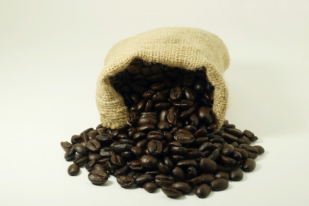 Coffee beans that are poured out of the bag on white background.