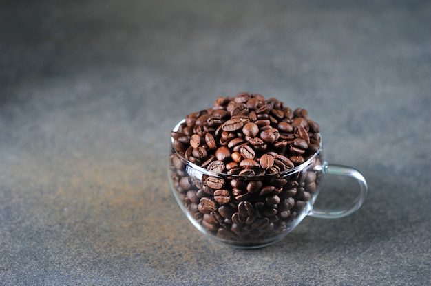 Coffee beans in transparent glass Cup on gray