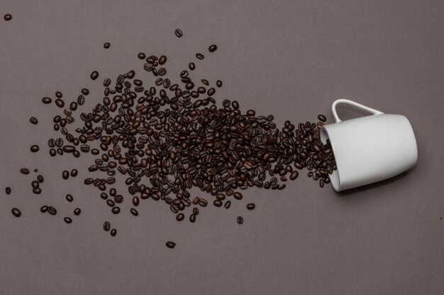 Coffee beans and white cup on coloured background