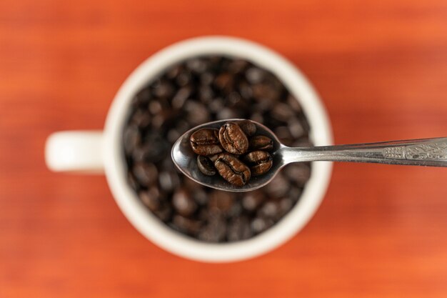 Coffee beans in white cup, top view