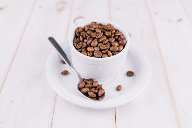 Coffee beans in a white cup on a wooden table