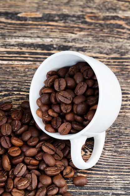 飲み物用の全体の形のコーヒー豆、カップに入った芳香性のコーヒー豆、マグカップでおいしいコーヒーを作るためのコーヒー豆
