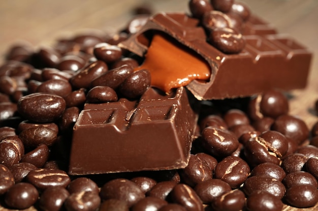 Coffee beans with chocolate glaze and dark chocolate on wooden background