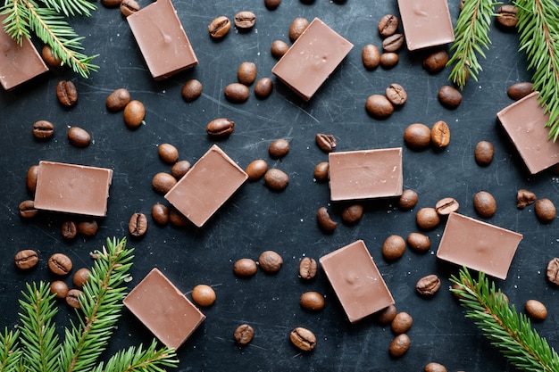 黒の背景の平面図上のチョコレートの部分とコーヒー豆