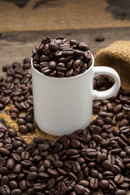 coffee beans with white cup on wooden table