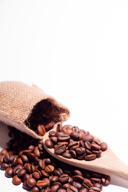 Chicchi di caffè con bianco, cucchiaio di legno e sacco