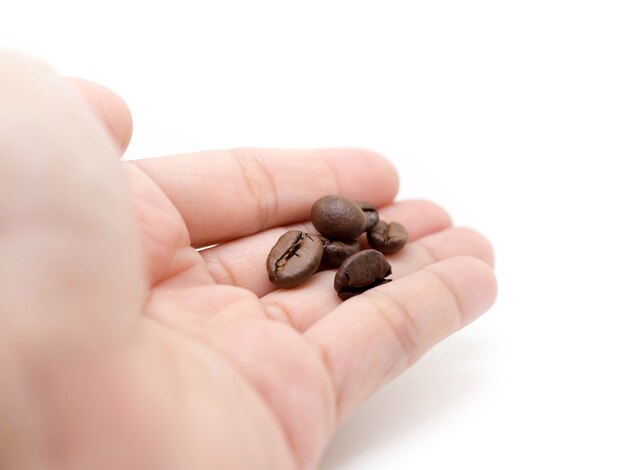 Foto chicchi di caffè in mano della donna (plam) su sfondo bianco.