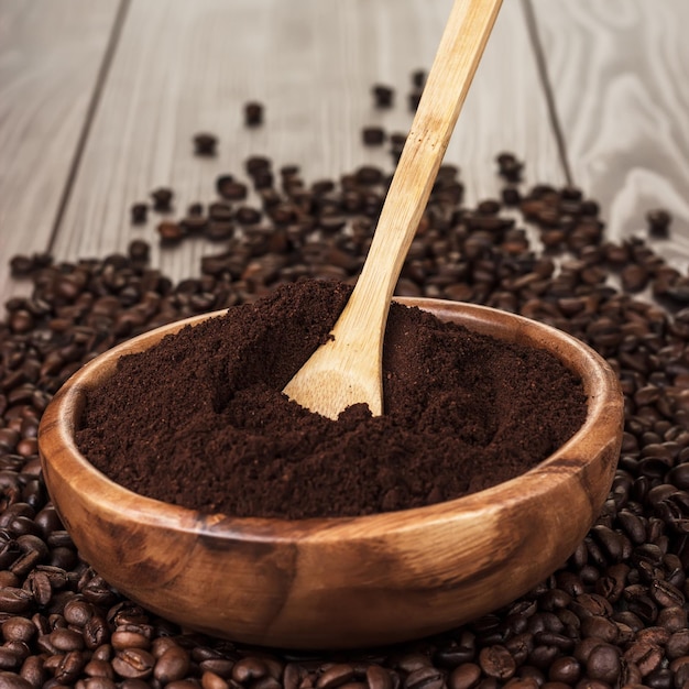 Coffee beans and wooden bowl full of ground coffee