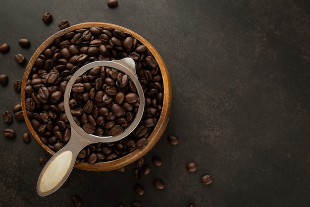 Coffee beans in wooden bowl on grunge background.