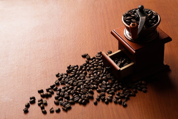 Кофейные зерна и деревянная кофемолка на деревянном столе