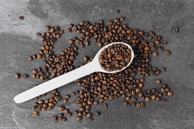 Coffee beans on wooden spoon isolated on dark background