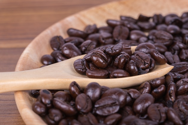 Coffee beans on a wooden spoon and plate on table 