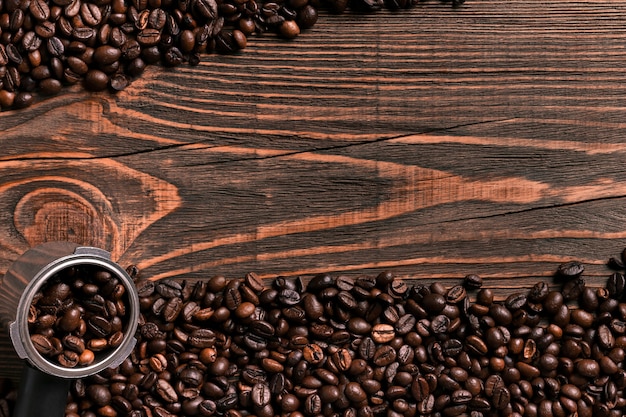 Chicchi di caffè sulla struttura di legno della tavola con la vista dello spazio della copia da