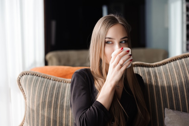 Caffè. bella ragazza che beve tè o caffè nella caffetteria