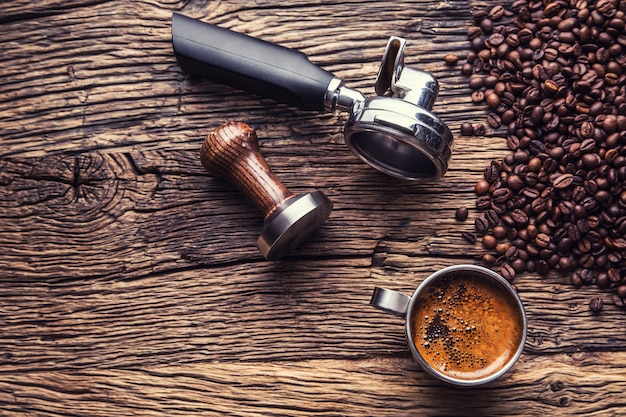 Coffee. Black coffee with coffee beans and portafilter on old oak wooden table.