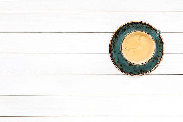 Coffee in blue cup on white wooden table. Top view, copy space