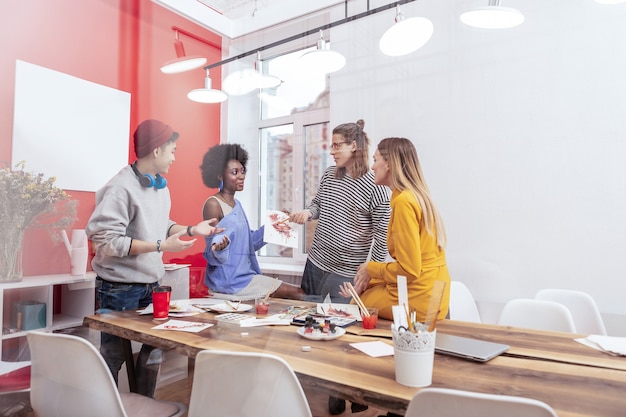 Caffè e brainstorming. quattro studenti intelligenti moderni che bevono caffè e fanno brainstorming