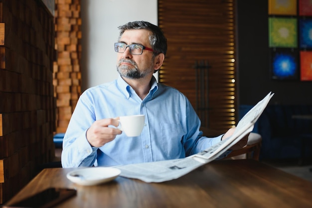 Coffee break man drinking coffee and reading newspaper in cafe bar