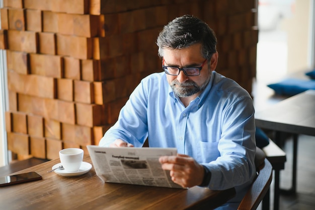 コーヒーを飲み、カフェバーで新聞を読んでコーヒーブレイク男