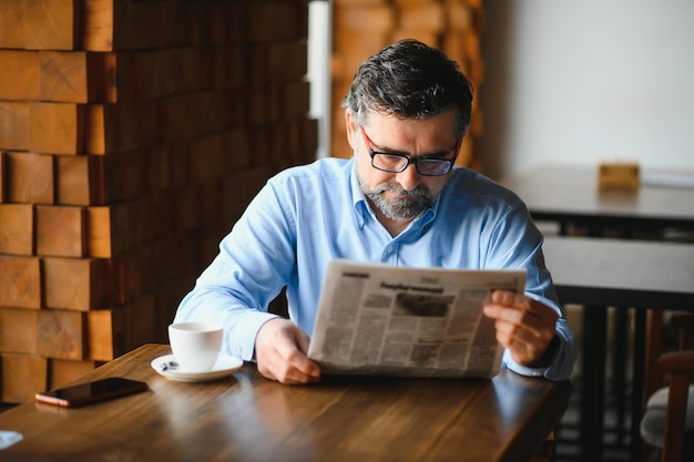 Coffee break man drinking coffee and reading newspaper in cafe bar