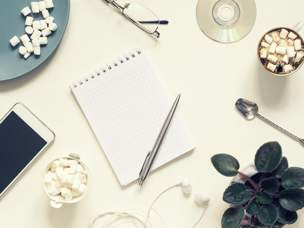 Coffee break in the workplace. Flat lay of phone, notepad, flowerpot and coffee with copy space