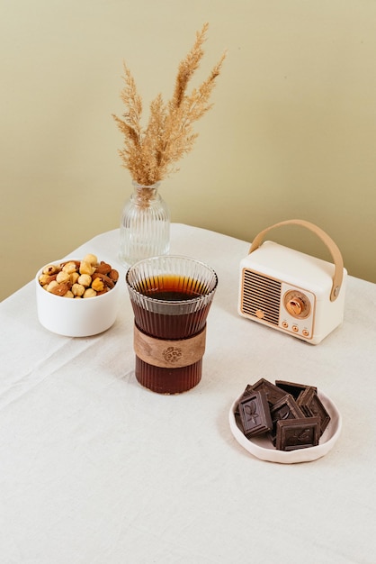 Coffee in a clear glass on the table milk in a milk jug chocolate in a plate