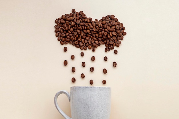 Coffee cloud and coffee rain abstract creative concept coffee mug and coffee beans beans on warm neutral background