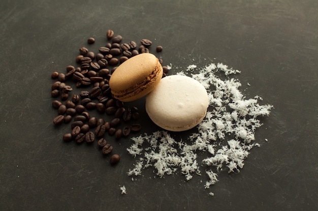 Coffee and coconut macaroons on the dark background with coffee beans and coconut chips.