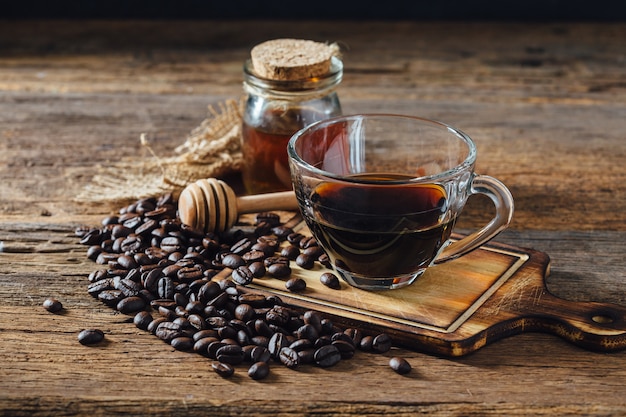 Caffè e chicchi di caffè con miele sul tavolo di legno