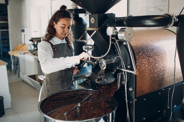 커피 로스팅 과정에서 로스터 기계에서 커피 냉각. 젊은 여성 작업자 바리스타 믹싱 냉각 커피 콩
