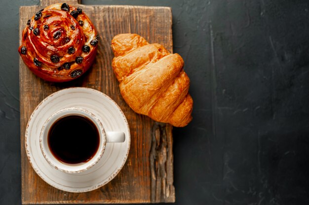 Coffee and croissant, bun on a stone table. morning breakfast, with copy space for text