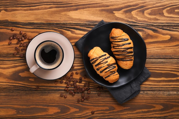 コーヒーとクロワッサンエスプレッソコーヒーとチョコレートと古い木製のテーブルのクロワッサン完璧なクロワッサン朝の朝食素朴なスタイル上面図モックアップ