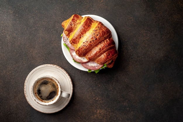 coffee and croissant with sausage, cheese and salad on a stone background. Breakfast concept  with copy space for your text