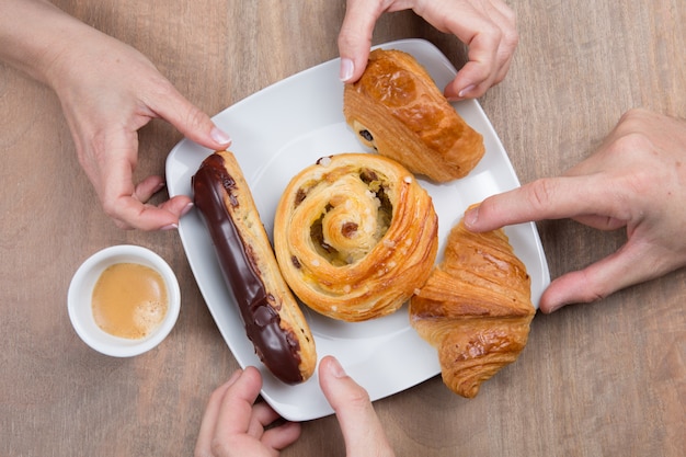 Coffee and croissants in cafe, hands of couple a closeup