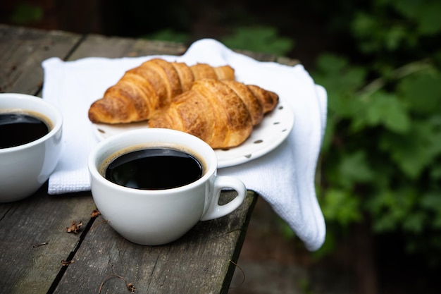 Coffee and croissants on old rustic wooden table