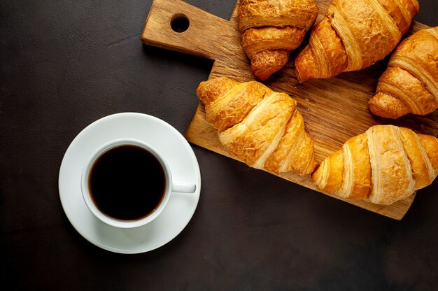 coffee and croissants on wooden cutting board